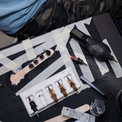 Close-up of a tattoo setup on a station tray covered with a black dental bib