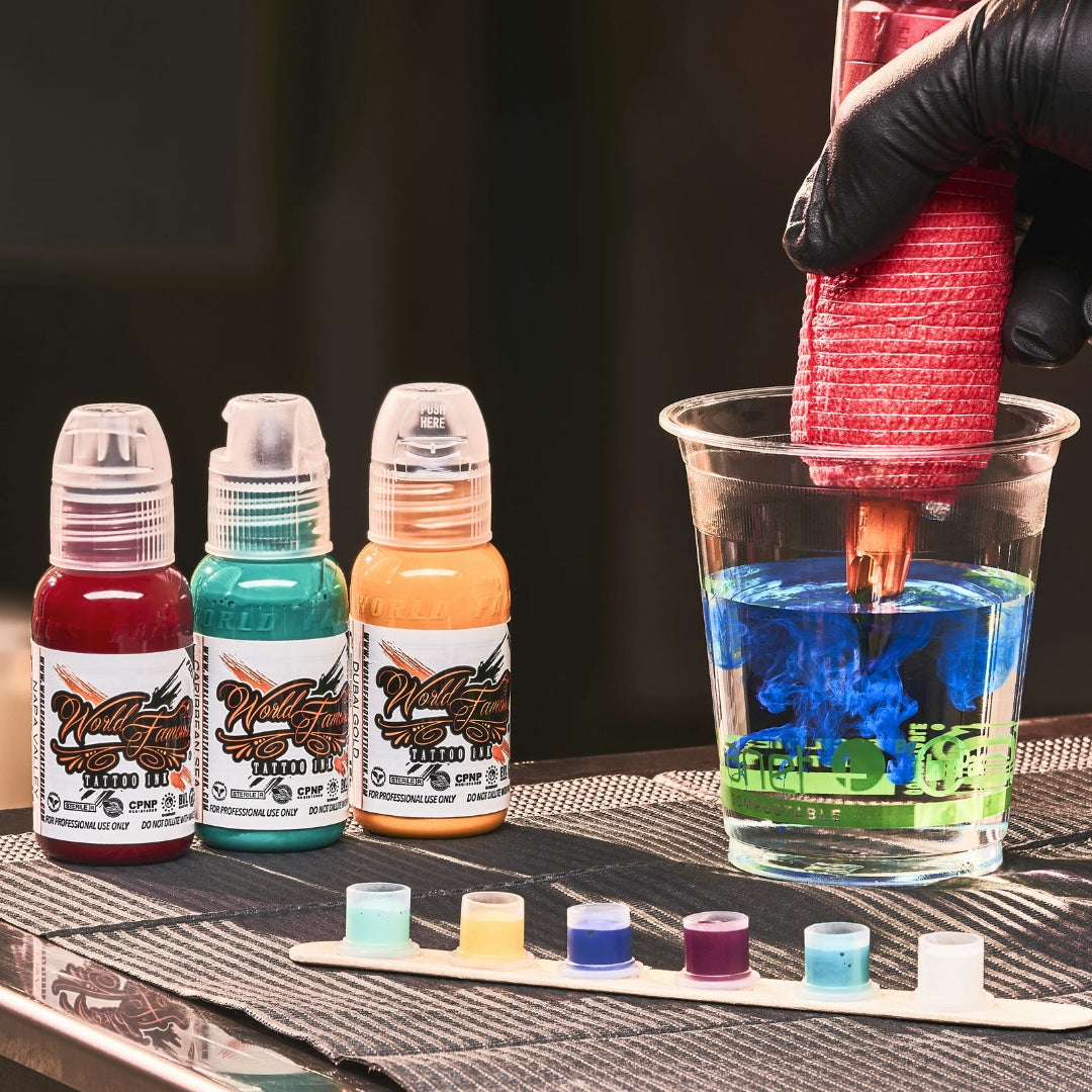 Close-up of tattoo artist setup with three World Famous tattoo inks and a cup of rinse water Your Complete Guide to Color Packing Like a Pro