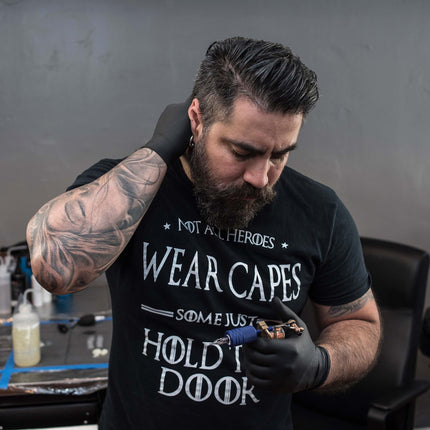 Tattoo artist with beard and latex gloves looking at his tattoo machine