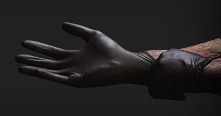 Tattoo artist putting on latex black tattoo glove