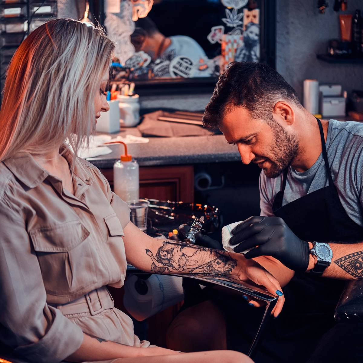Tattoo artist tattooing a client