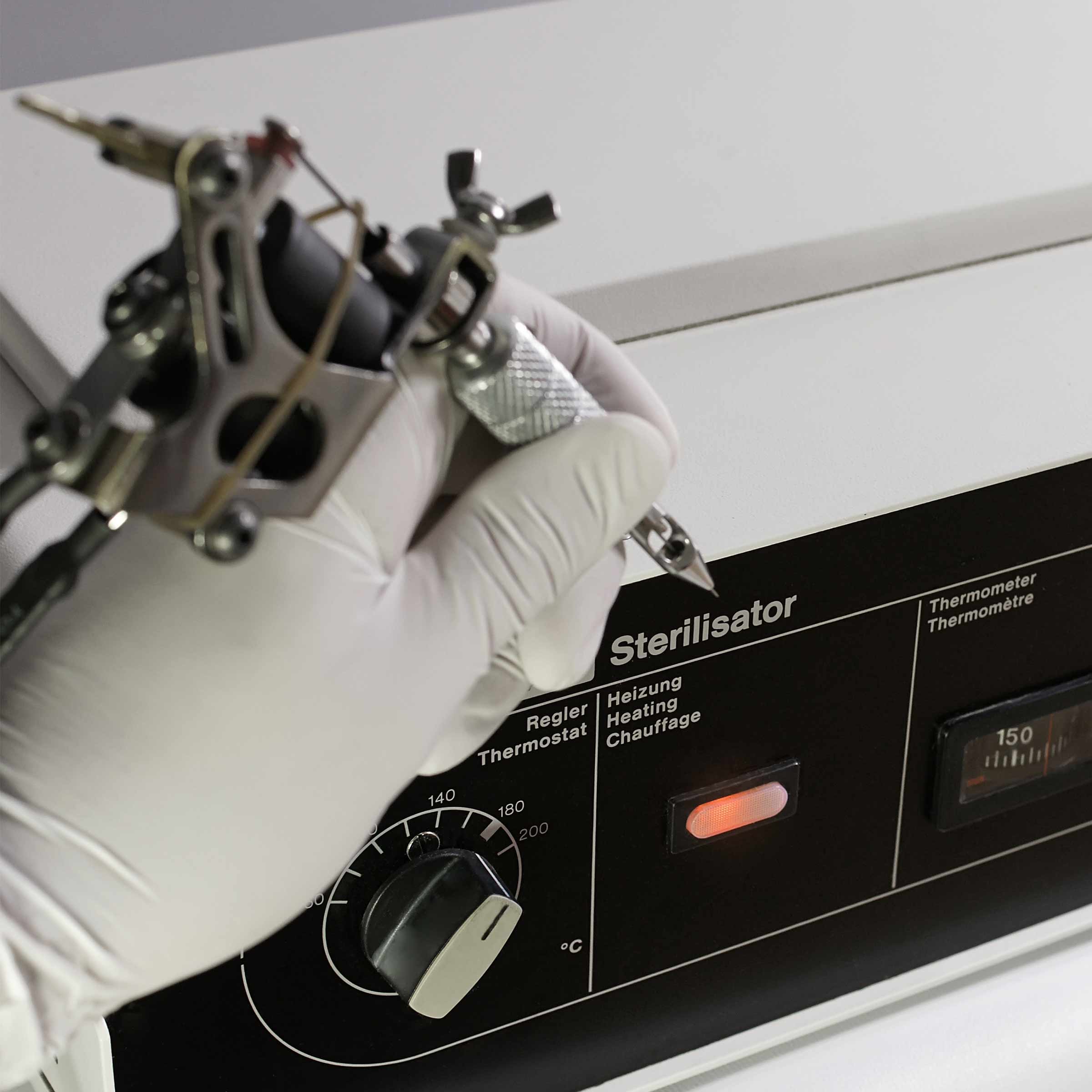 Tattoo machine next to autoclave Tattoo & Piercing Sterilization Methods