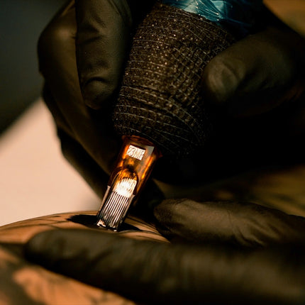 Close-up of Triton needles tattooing a client