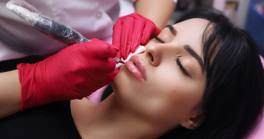 Client receiving permanent makeup lip blush procedure with pink pigment
