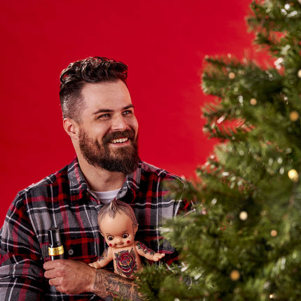 Tattooed man holding the A Pound of Flesh Cutie Doll by a Christmas Tree