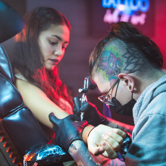 Tattoo artist working on a client's arm tattoo