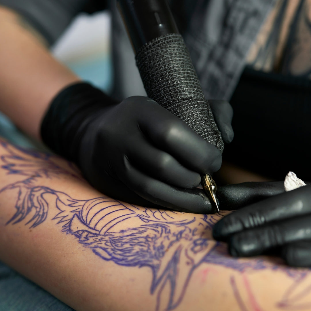 Tattoo artist working on a forearm tattoo How to Make a Tattoo Flow