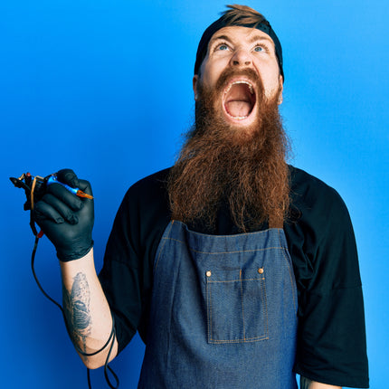 Frustrated tattoo artist crying out loud while holding a tattoo machine