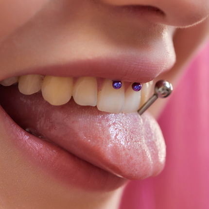 A woman with a lip frenulum and tongue piercing.