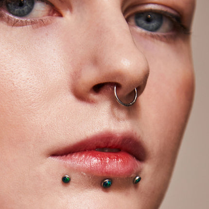 Close-up of person with facial piercings|||Threadless labret posts with jeweled tops|Variety of anodized black labret shafts in different labret lengths
