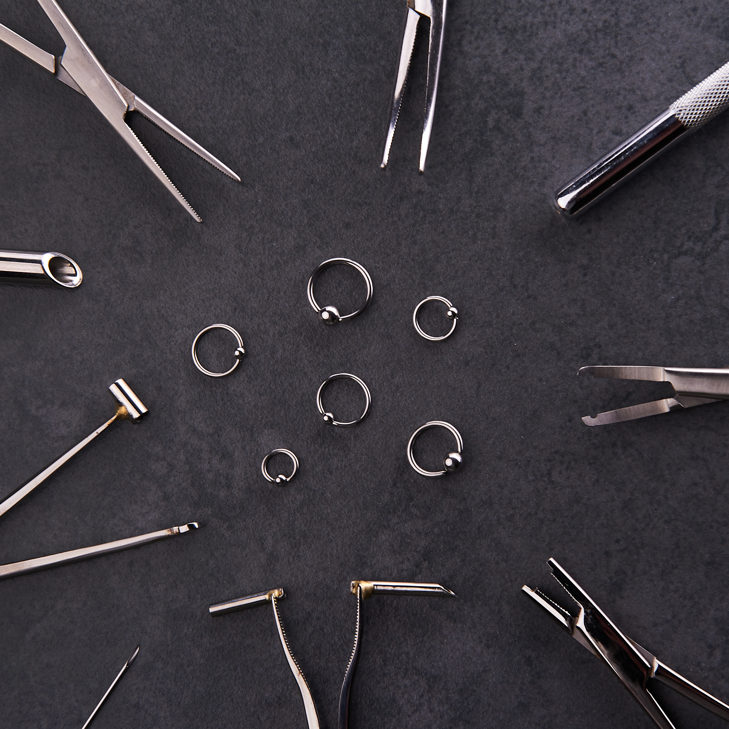 Circle of piercing tools and forceps around captive bead rings Choosing the Right Piercing Needle: A Beginner's Guide to Quality Tools