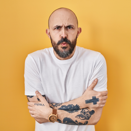 Tattooed man against yellow background.