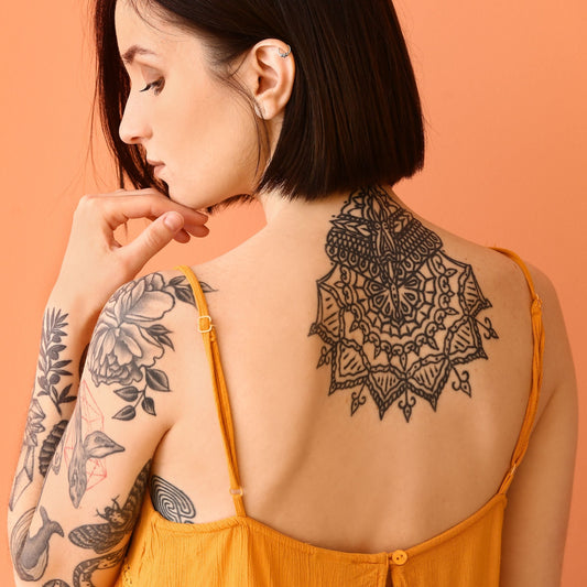 A woman showing her back and arm tattoos.