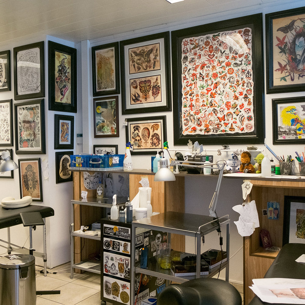 Empty tattoo shop with flash sheets framed on the walls How to Stay Busy During the Tattoo Slow Season