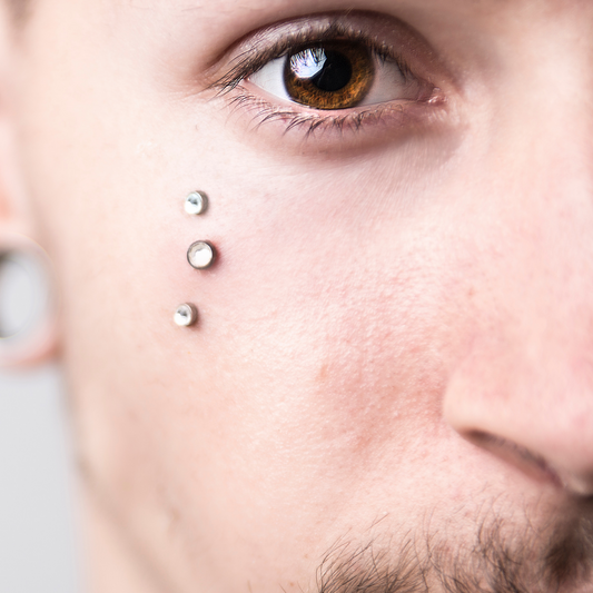 Half front male profile of 3 dermal piercings on the face.