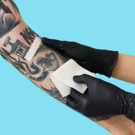 Closeup of a bandage being peeled off a new tattoo