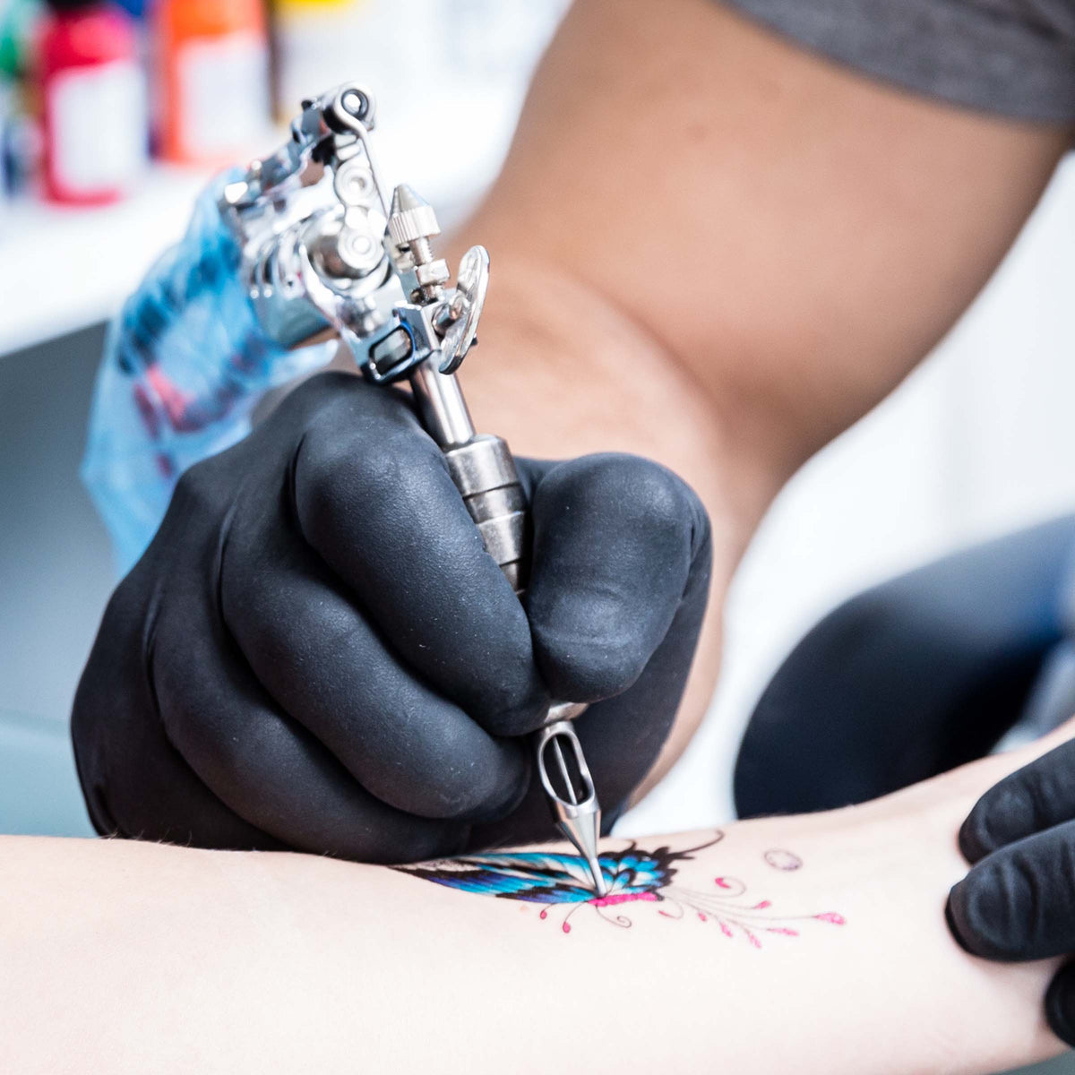 Close-up of tattoo artist's hand working on an arm tattoo