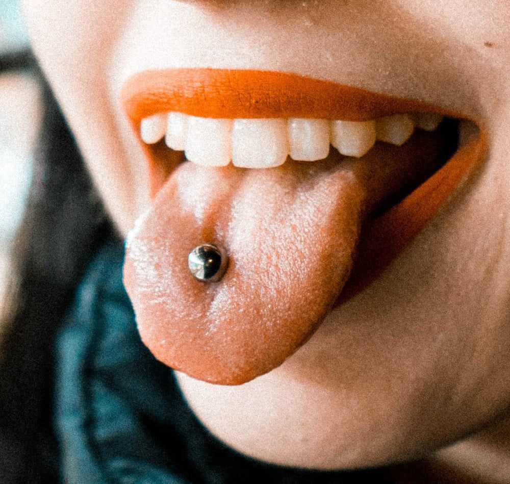 Photo of smiling mouth with tongue piercing Tongue Piercing FAQs