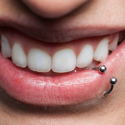 Close-up of mouth with bottom lip piercing|Smiling Girl With Lip Piercings, a Septum Piercing and a Nostril Piercing