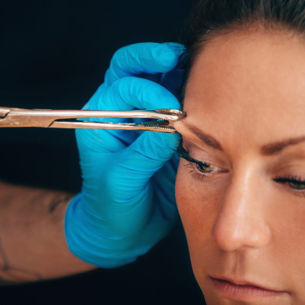 A woman getting an eyebrow piercing.