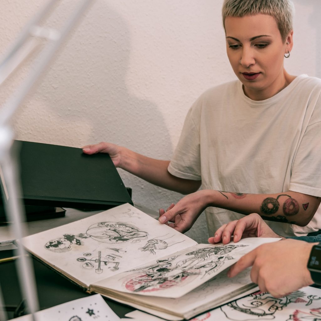 Tattoo artist rifling through a print portfolio