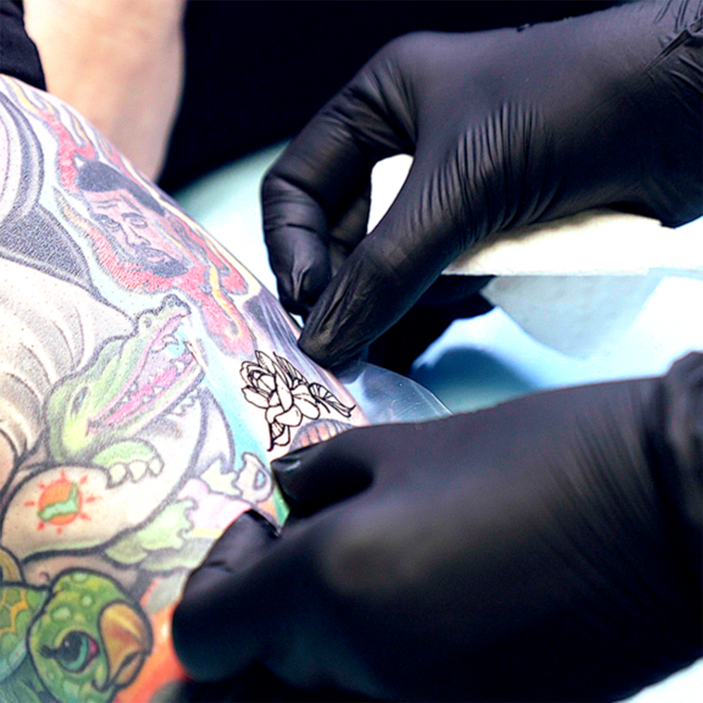 Tattoo artist applying tattoo stencil to client's skin