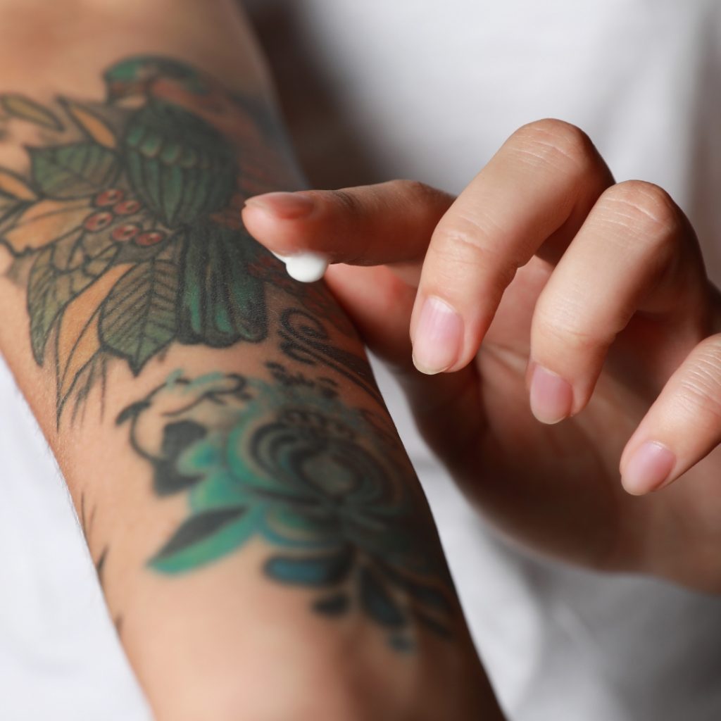 Close-up of a client using tattoo lotion on their tattoo