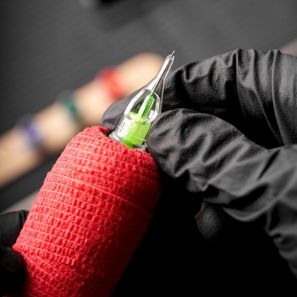 Stellar needle cartridge in a cartridge tattoo grip with red cohesive wrap