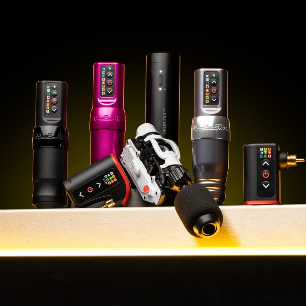 Variety of tattoo machines on a workstation counter with tattoo battery packs