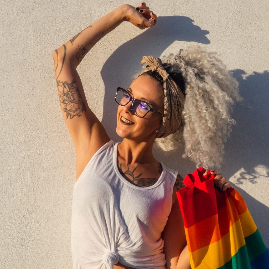 Flexing tattoo artist with Pride flag at a Pride event