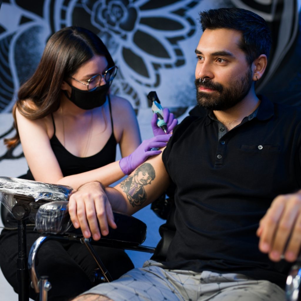 Guest tattoo artist working on a client's arm tattoo