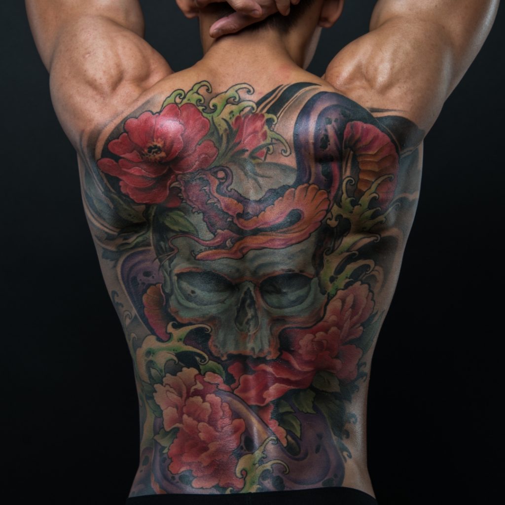 A full back tattoo with skull in the center.
