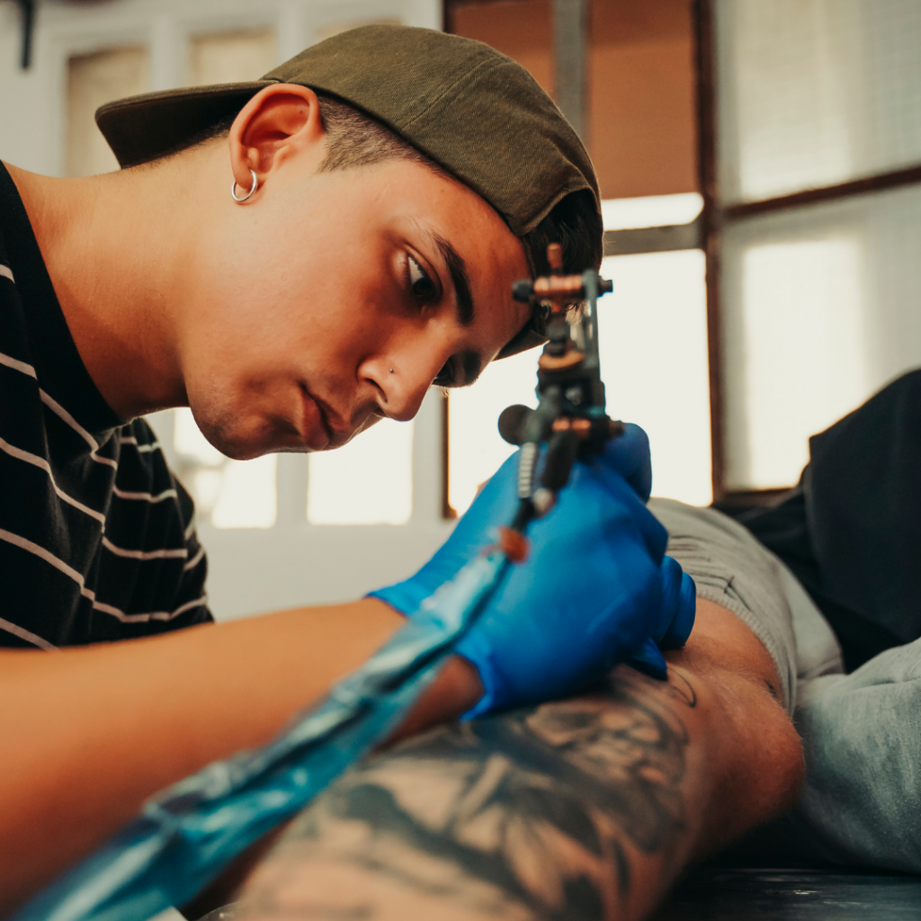 Artist tattooing a client's leg.