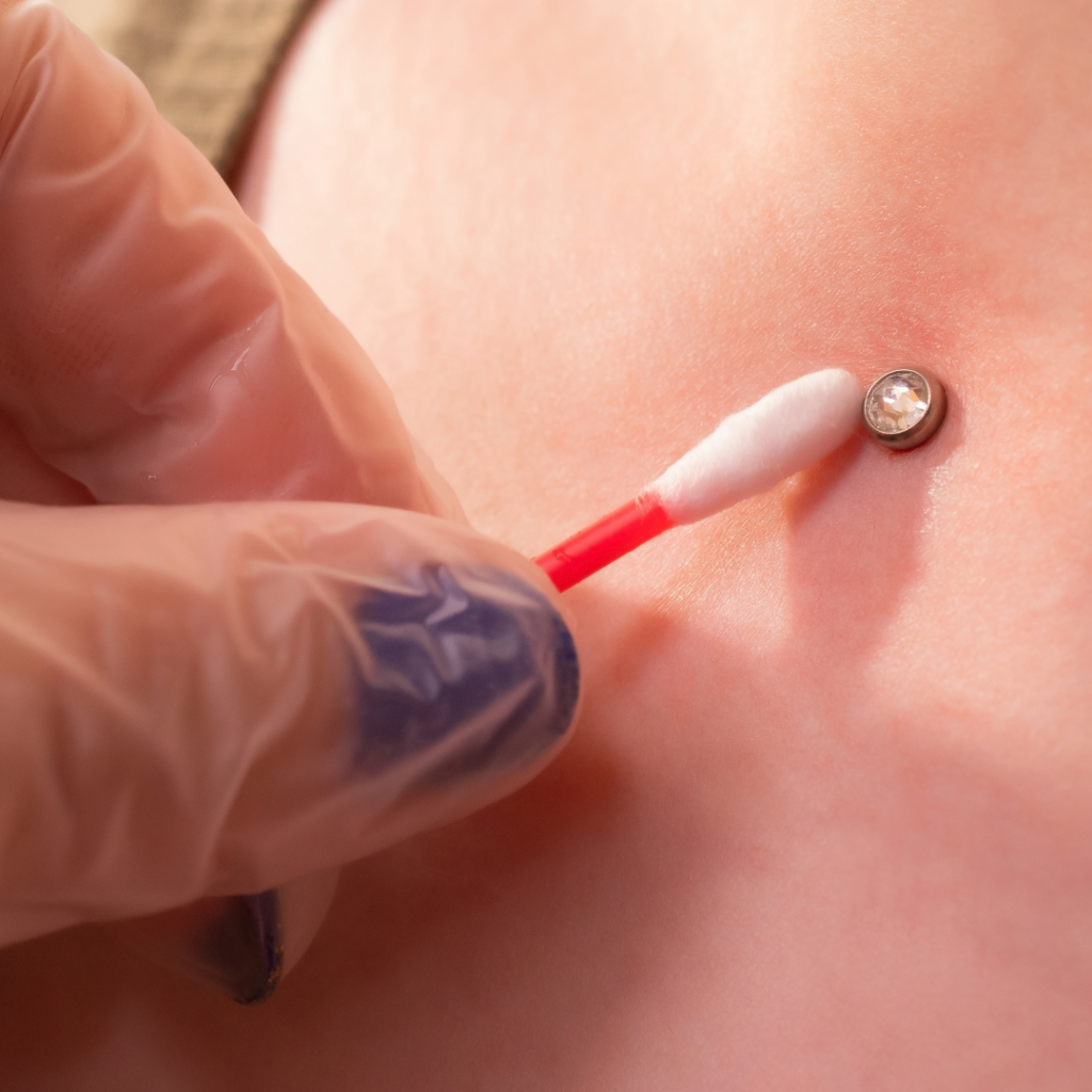 Dermal piercing aftercare application with a cotton swab.