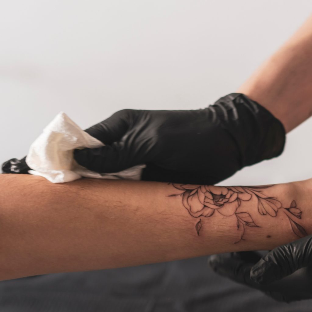 A tattoo artist wiping a client's arm.