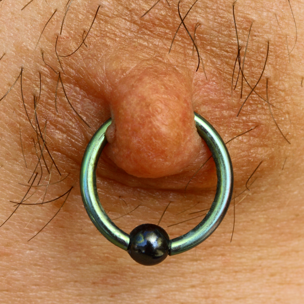 An extreme close-up of a nipple piercing ring.
