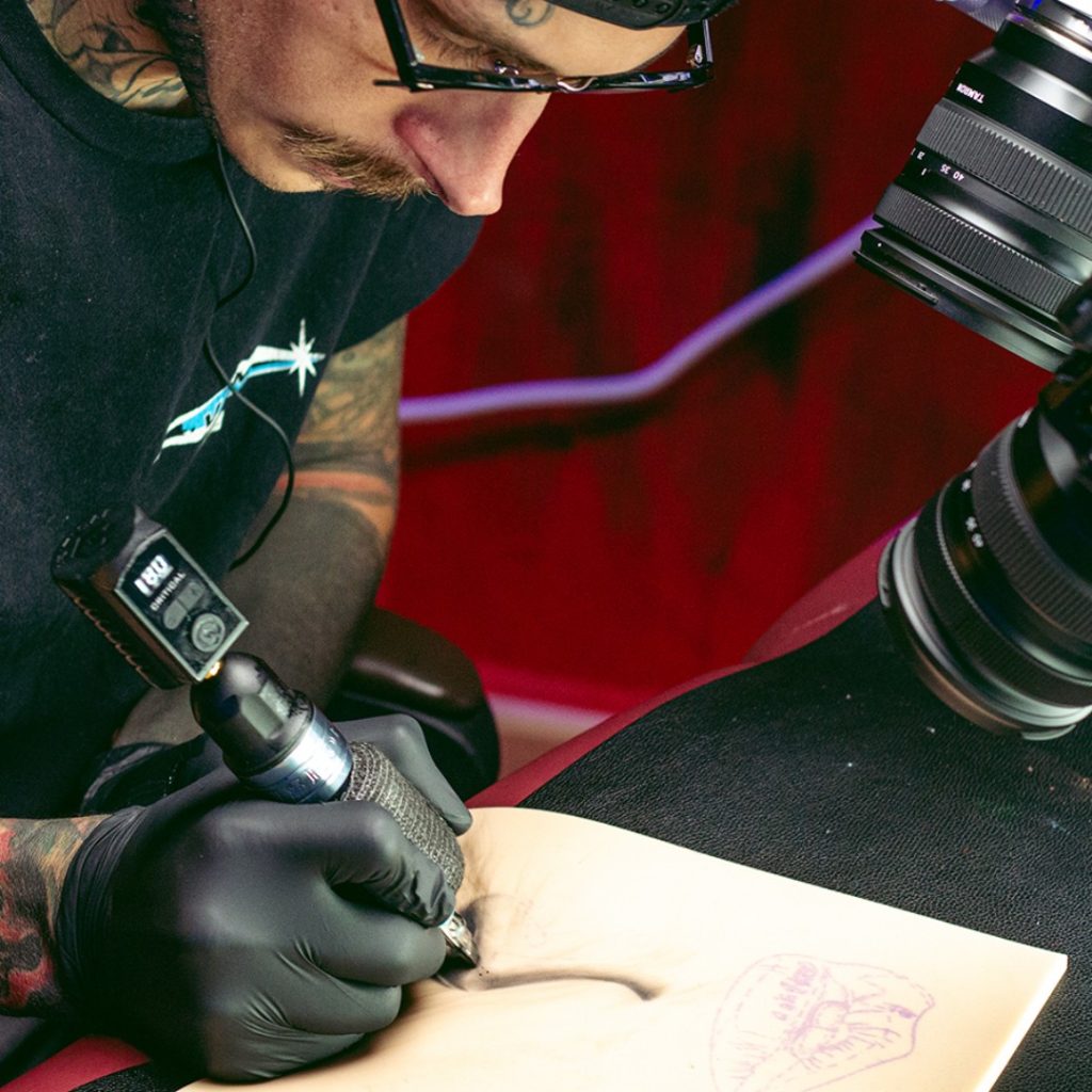 Artist tattooing a practice skin.