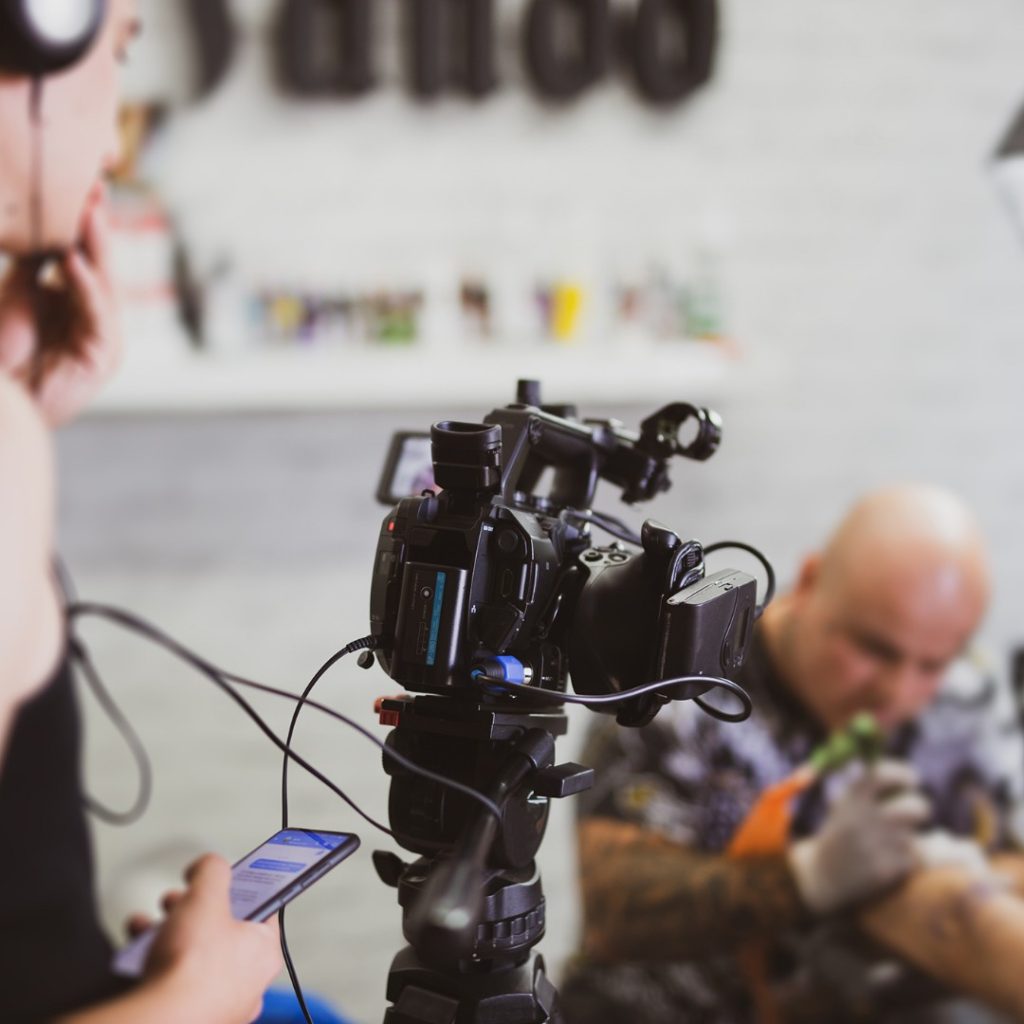 camerawoman filming a tattoo reality TV set.